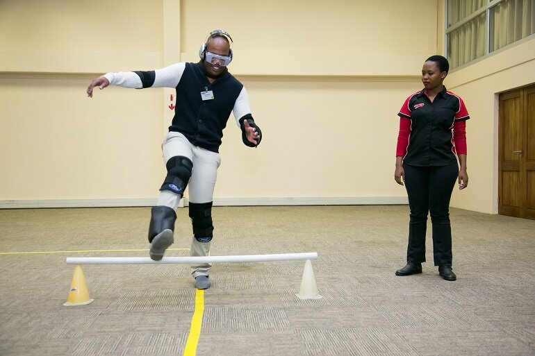 (Left) Ethol Mohale tries on the Drunk Suit as Derek Kirkby, Ford’s Driving Skills For Life training director in South Africa, explains the fascinating story behind the development of the suit by the Meyer-Hentschel Institute in Germany. (Right) A sober Gino Shelile from Ignition TV, stumbles as he demonstrates the effects of the Drunk Suit while trying to complete a simple walking exercise while Ethol Mohale from Ford’s Driving Skills For Life programme looks on.